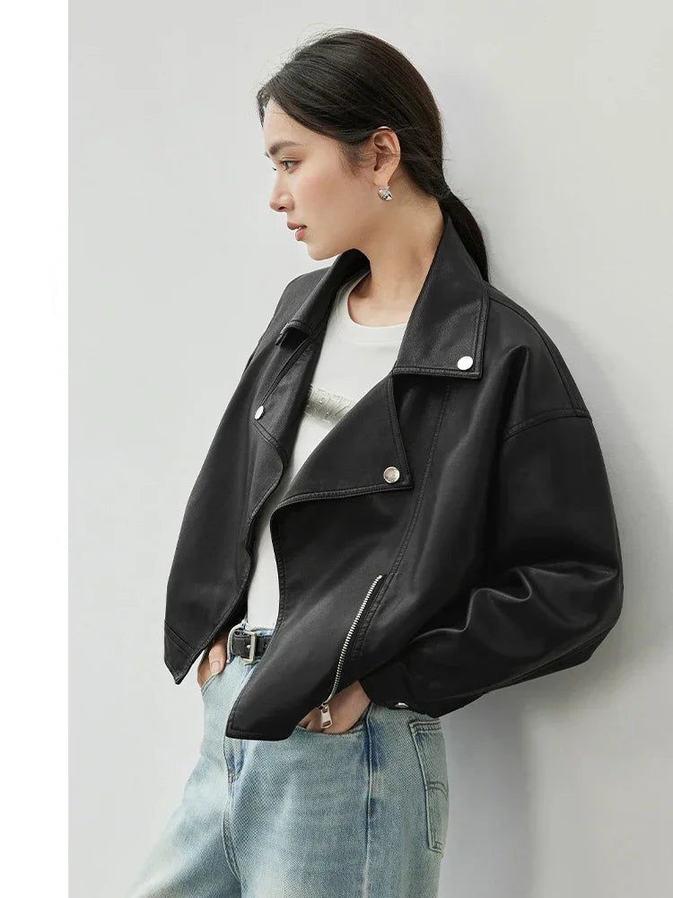 Woman wearing a black leather jacket and light blue jeans against a white background.