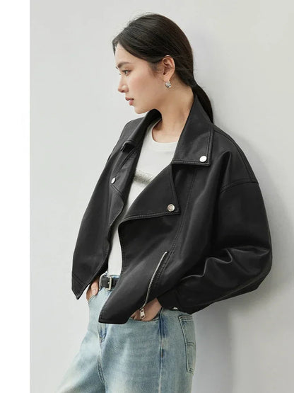 Woman wearing a black leather jacket and light blue jeans against a white background.