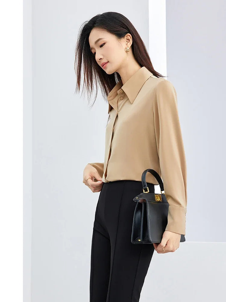 Woman wearing a beige blouse and black pants holding a black handbag on a white background with 'SENTUBILA' branding.