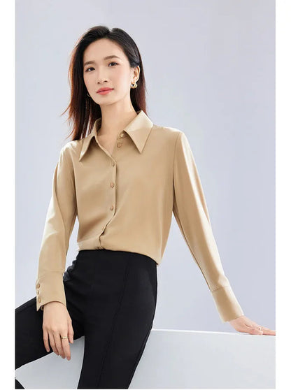 Woman wearing a beige blouse and black pants against a light gray background