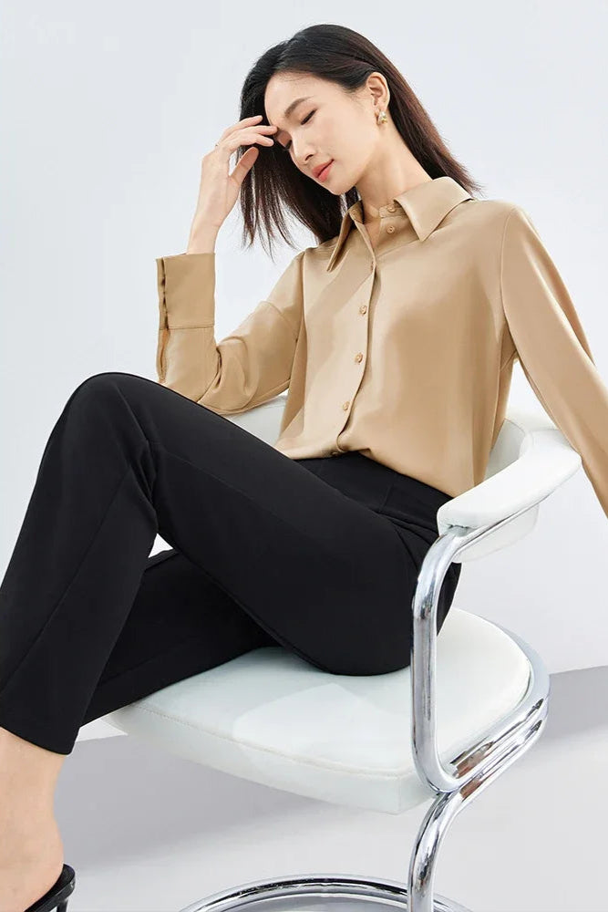 Woman sitting on a chair wearing a beige blouse and black pants, with 'SENTUBILA' branding.