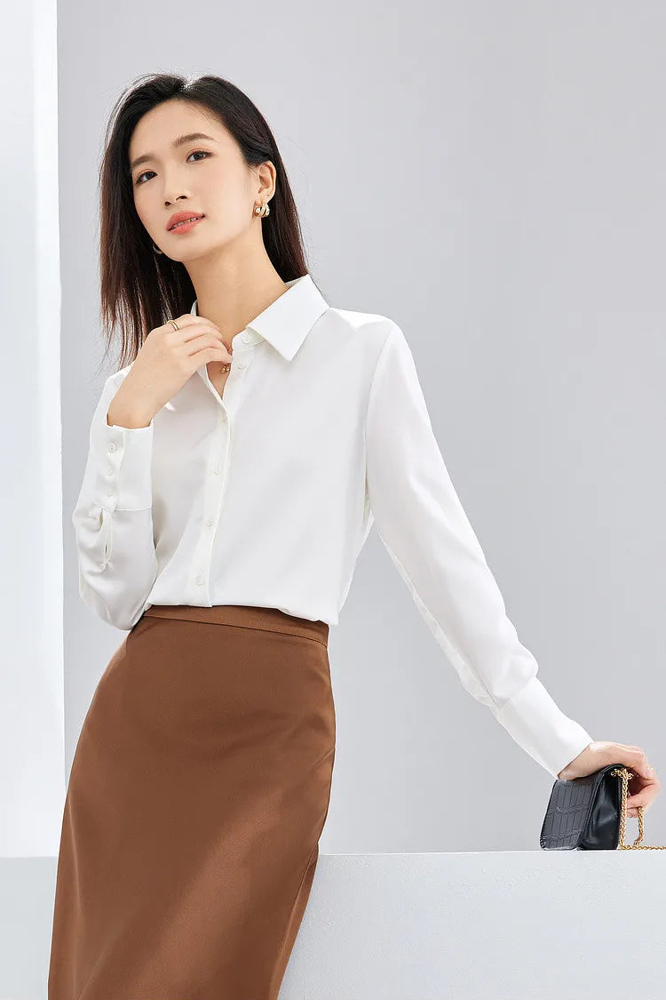 Woman wearing a white blouse and brown skirt on a light gray background